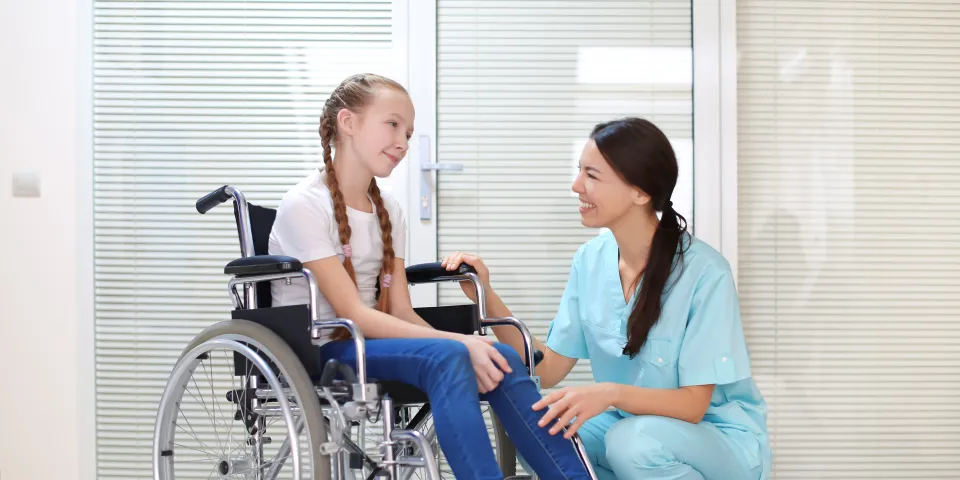 young girl in wheelchair talking to dental assistant