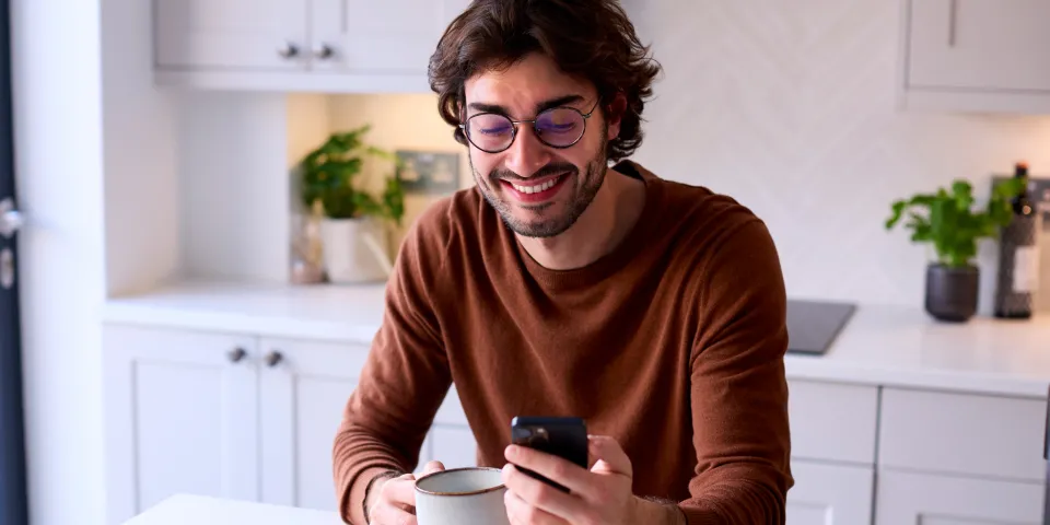 man on phone in kitchen wearing glasses